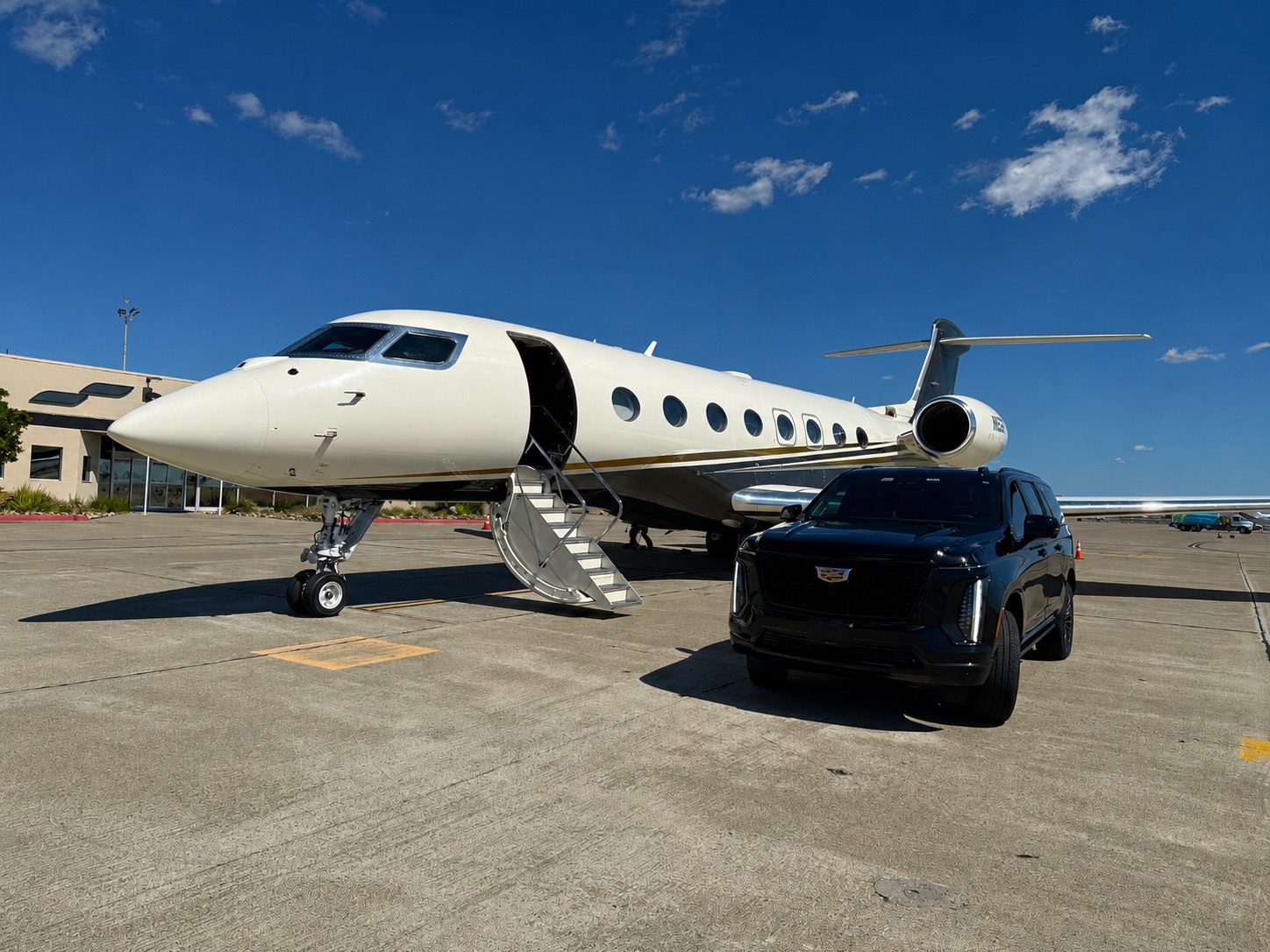 Black Cadillac Escalade parked next to a private jet on the tarmac