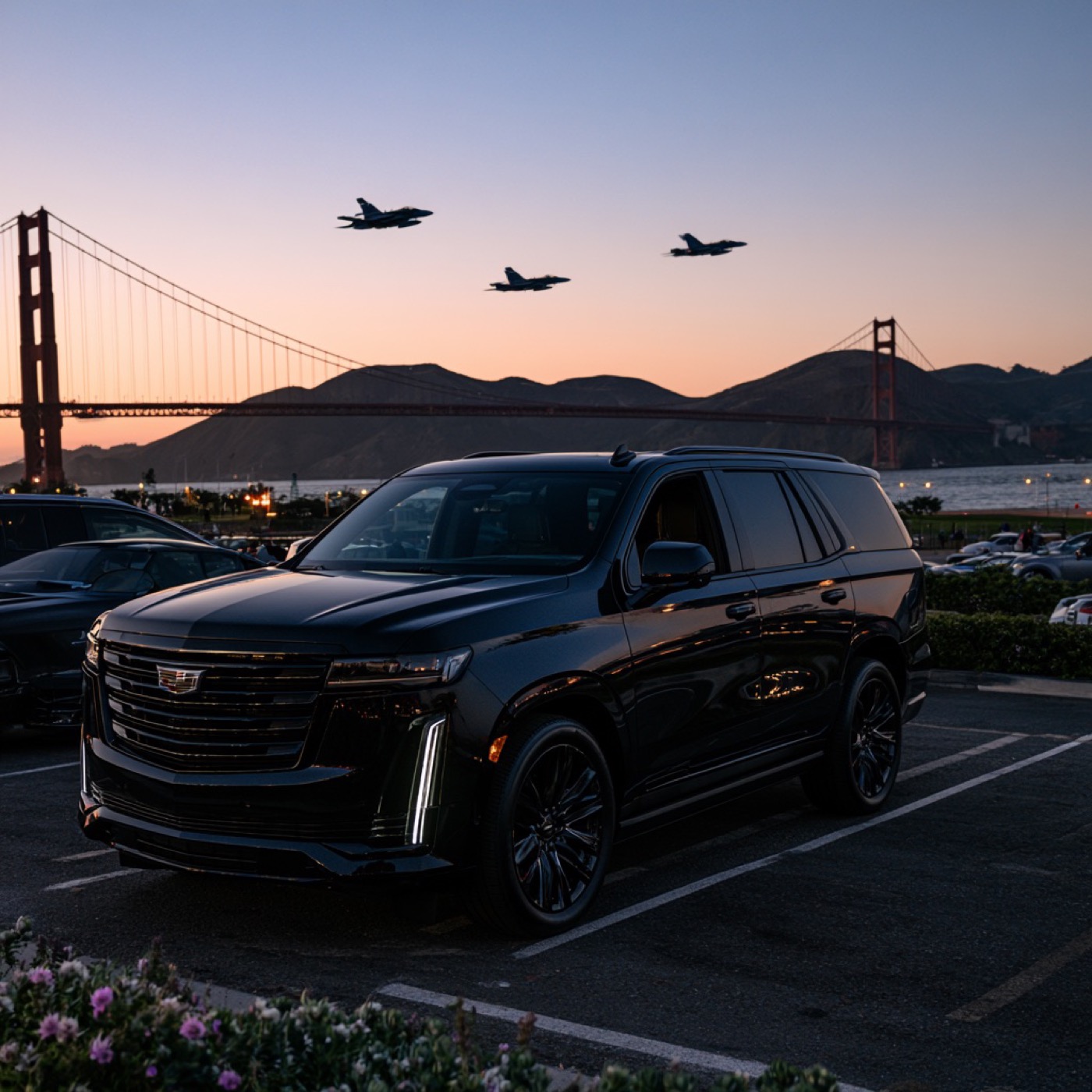 Black Cadillac Escalade parked near the Golden Gate Bridge as jets fly overhead at dusk