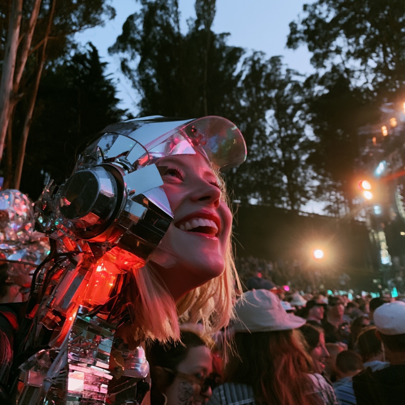 Festival-goer smiling in the crowd under stage lights at dusk